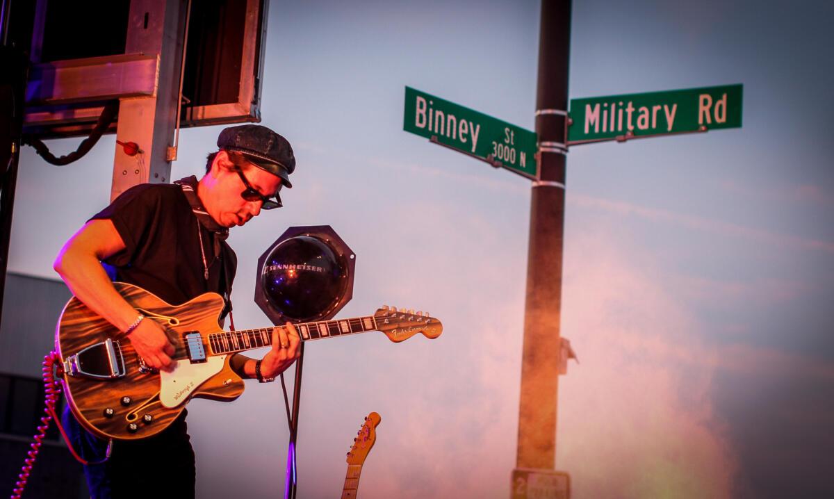 With the Military Road sign in the background, Adrian Quesada performs with Black Pumas at Waiting Room Outdoors in Omaha. 
